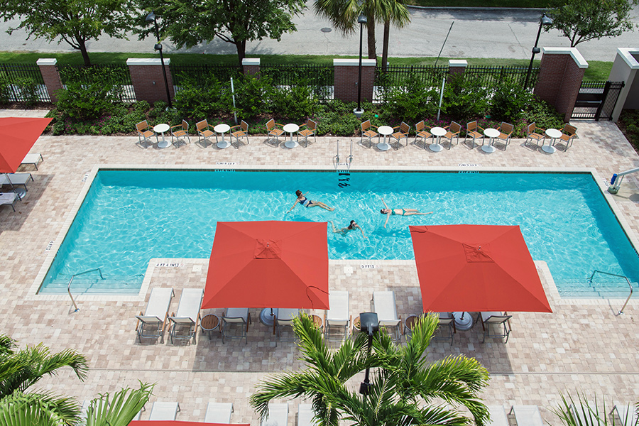 A pool with red umbrellas and palm trees