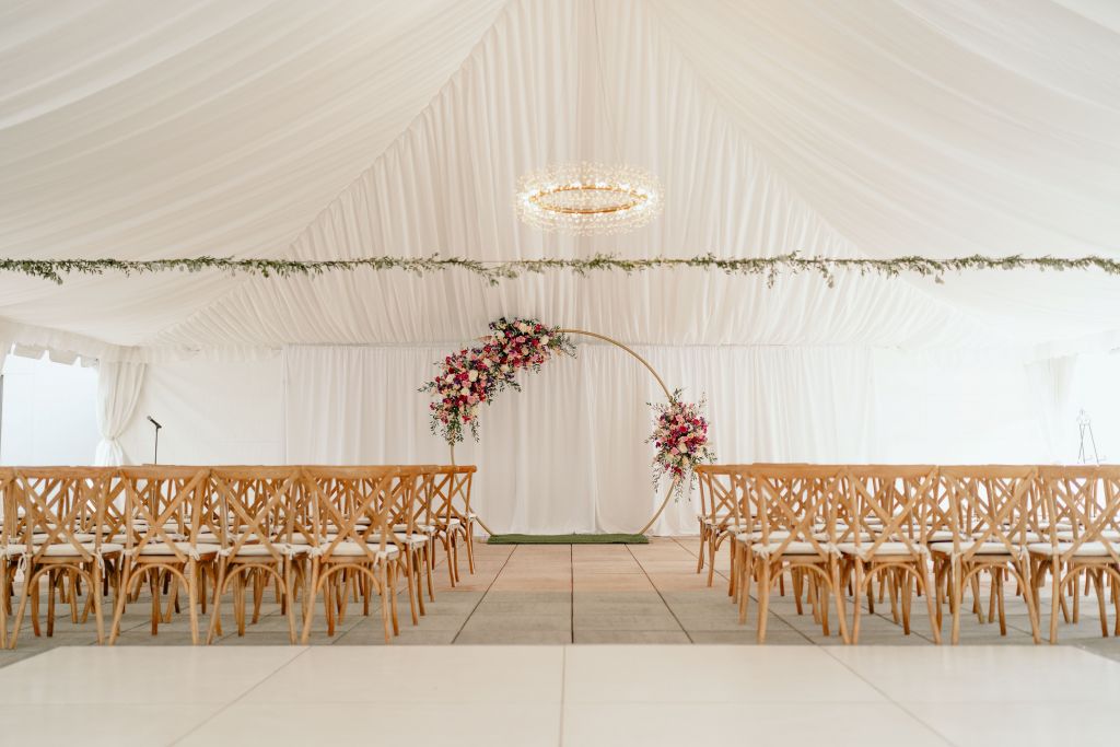 A white tent with chairs and a round arch