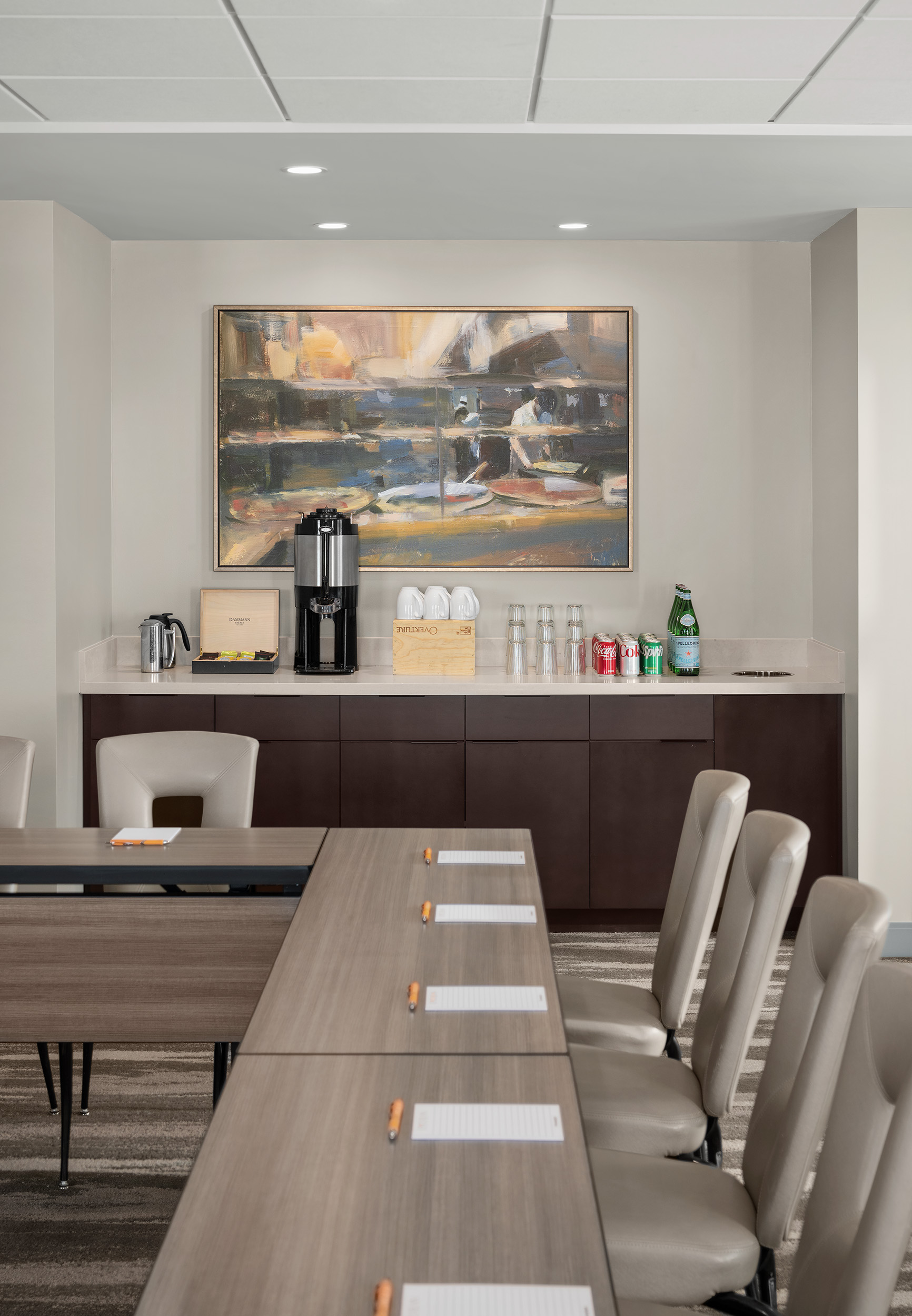 meeting room table in foreground with focus on beverage setup for coffee and sodas