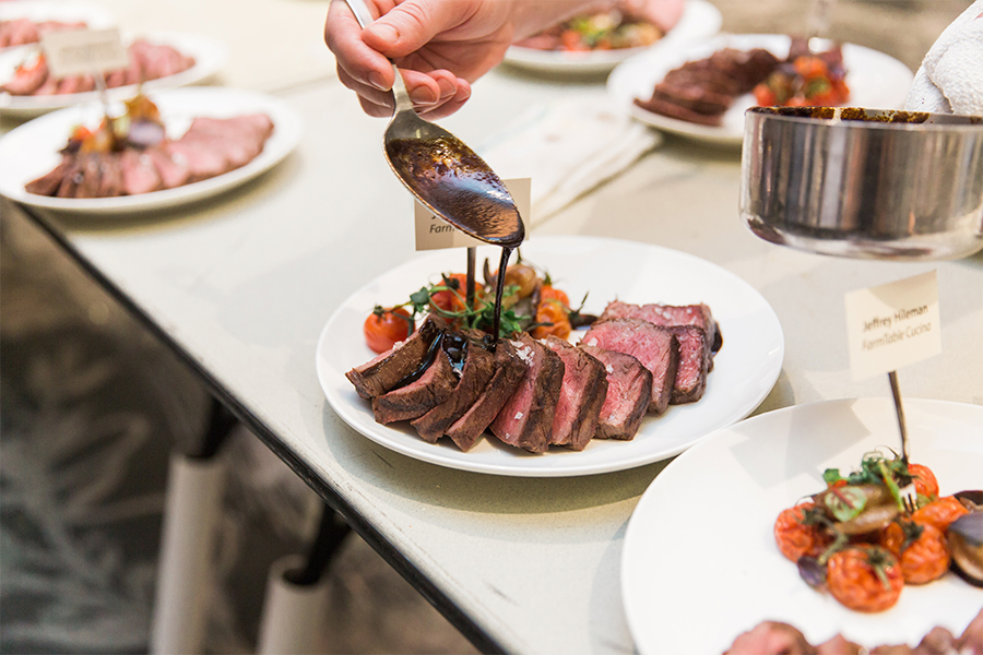 A person pouring sauce on a plate of meat