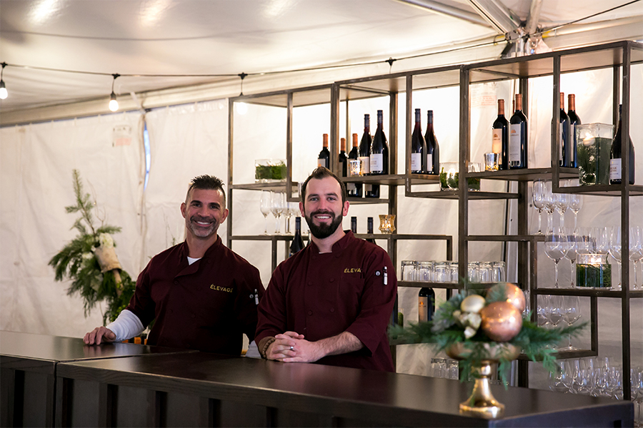 Two men standing behind a bar