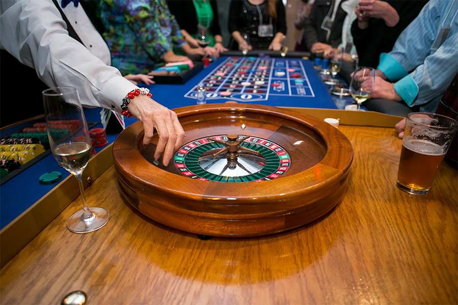 A roulette wheel on a table with people around