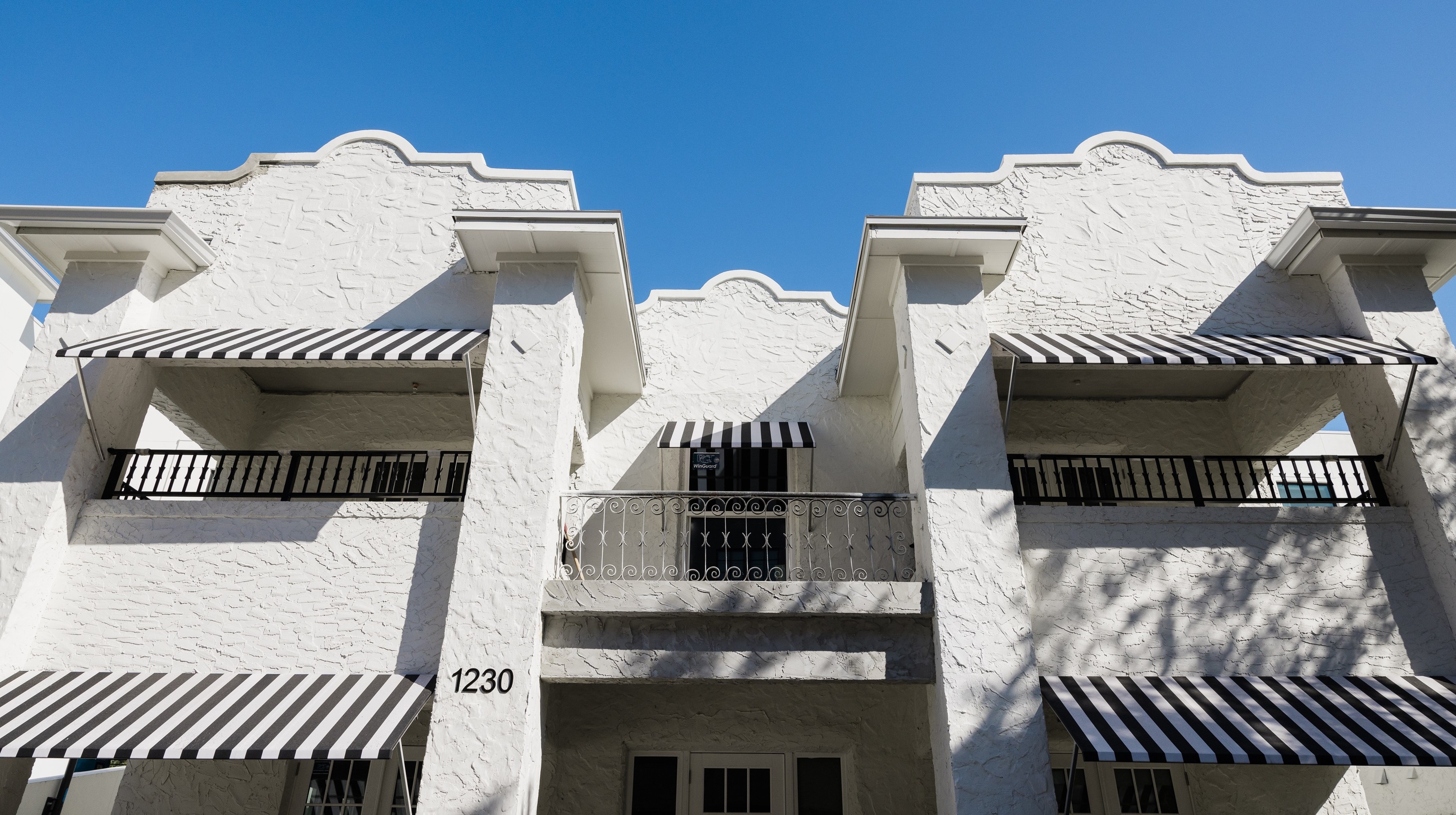 A white building with black and white awnings in Hyde Park District in South Tampa Florida across from Epicurean Hotel