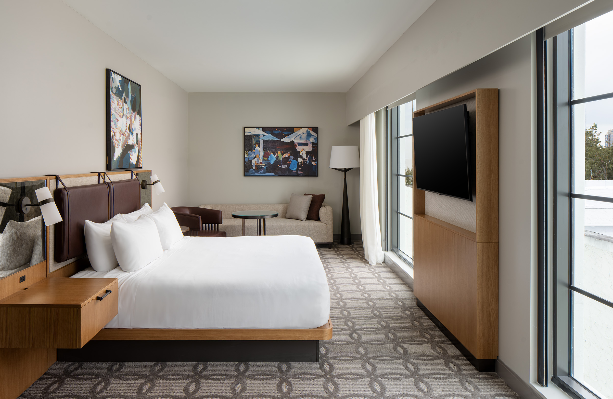 hotel guestroom with bed, tv mounted to wall and sofa bed