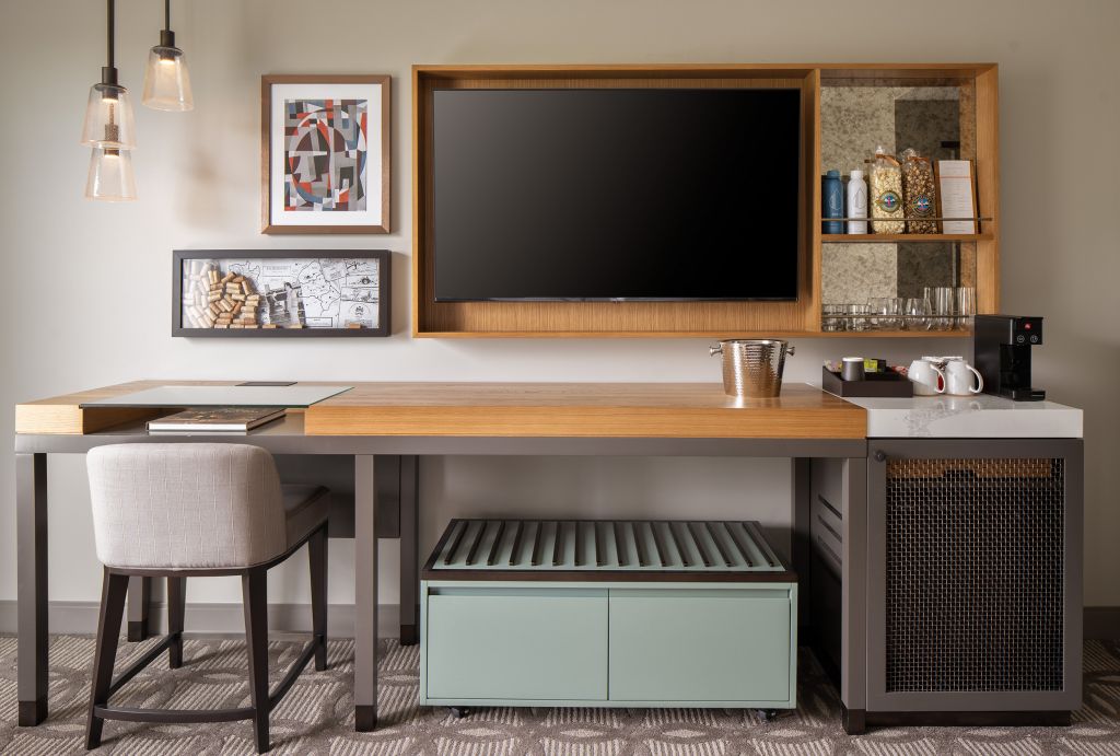 desk with TV mounted on wall, artisan pantry in hotel guest room