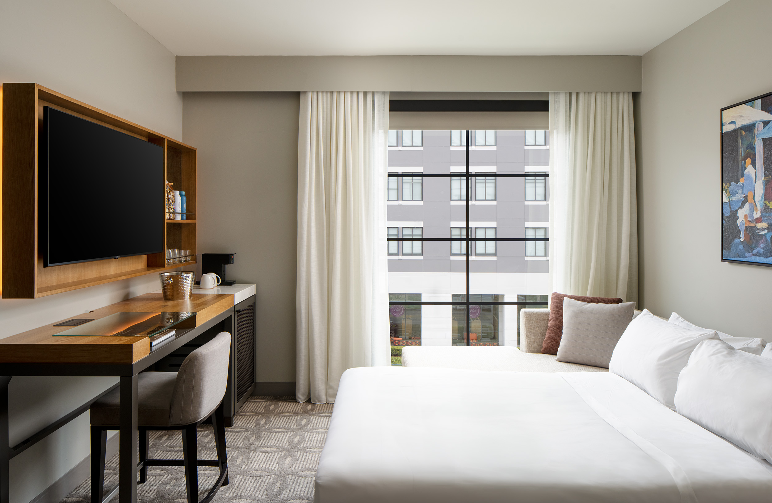 hotel guestroom with king bed and media desk with TV