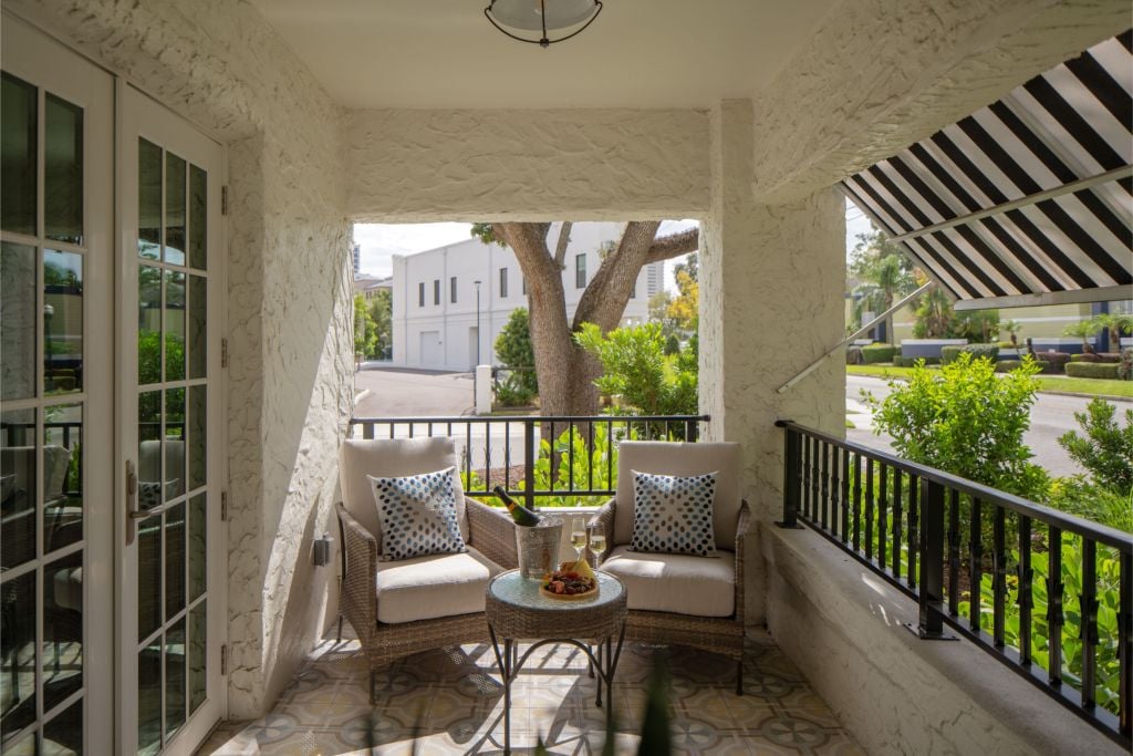 a covered balcony with two arm chairs and refreshments of a historic hotel apartment in Hyde Park District in South Tampa Florida across from Epicurean Hotel