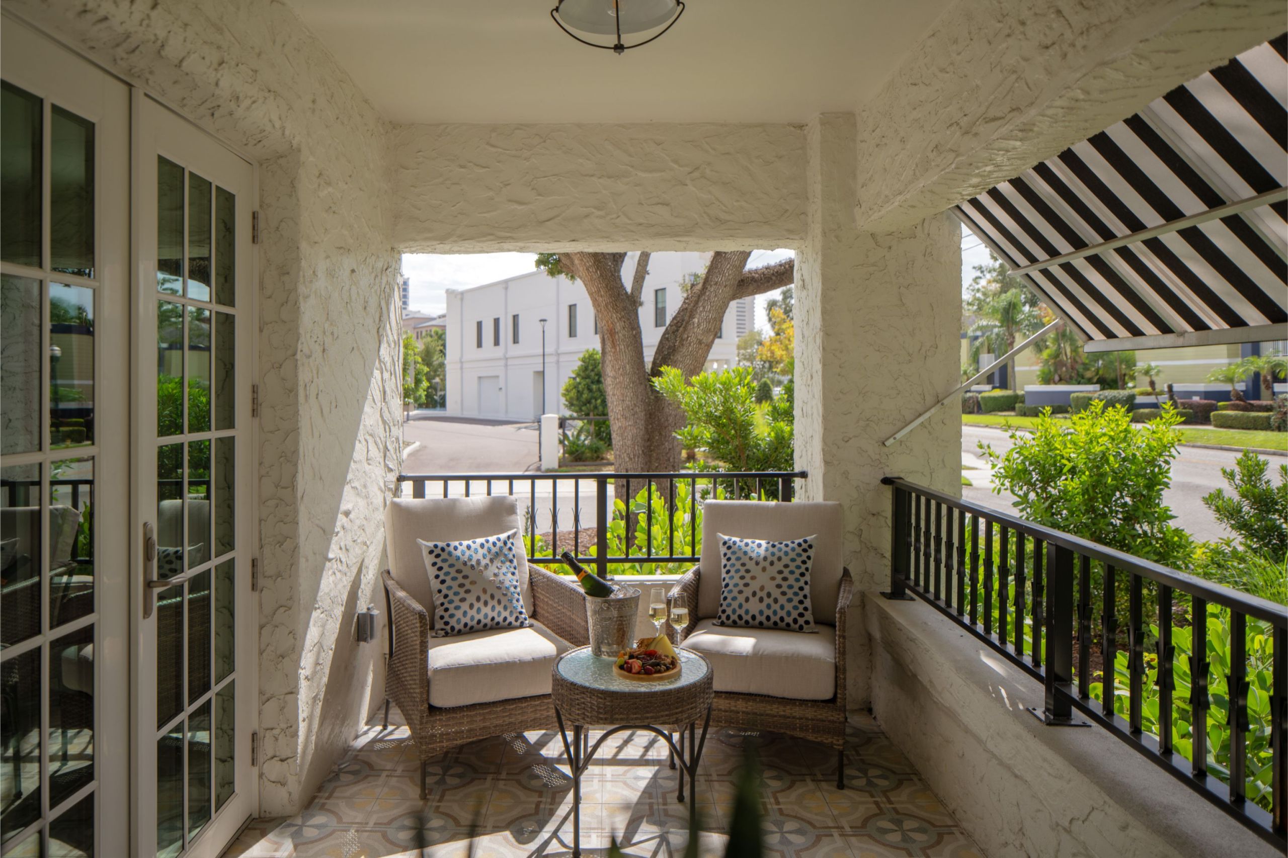 a covered balcony with two arm chairs and refreshments of a historic hotel apartment in Hyde Park District in South Tampa Florida across from Epicurean Hotel