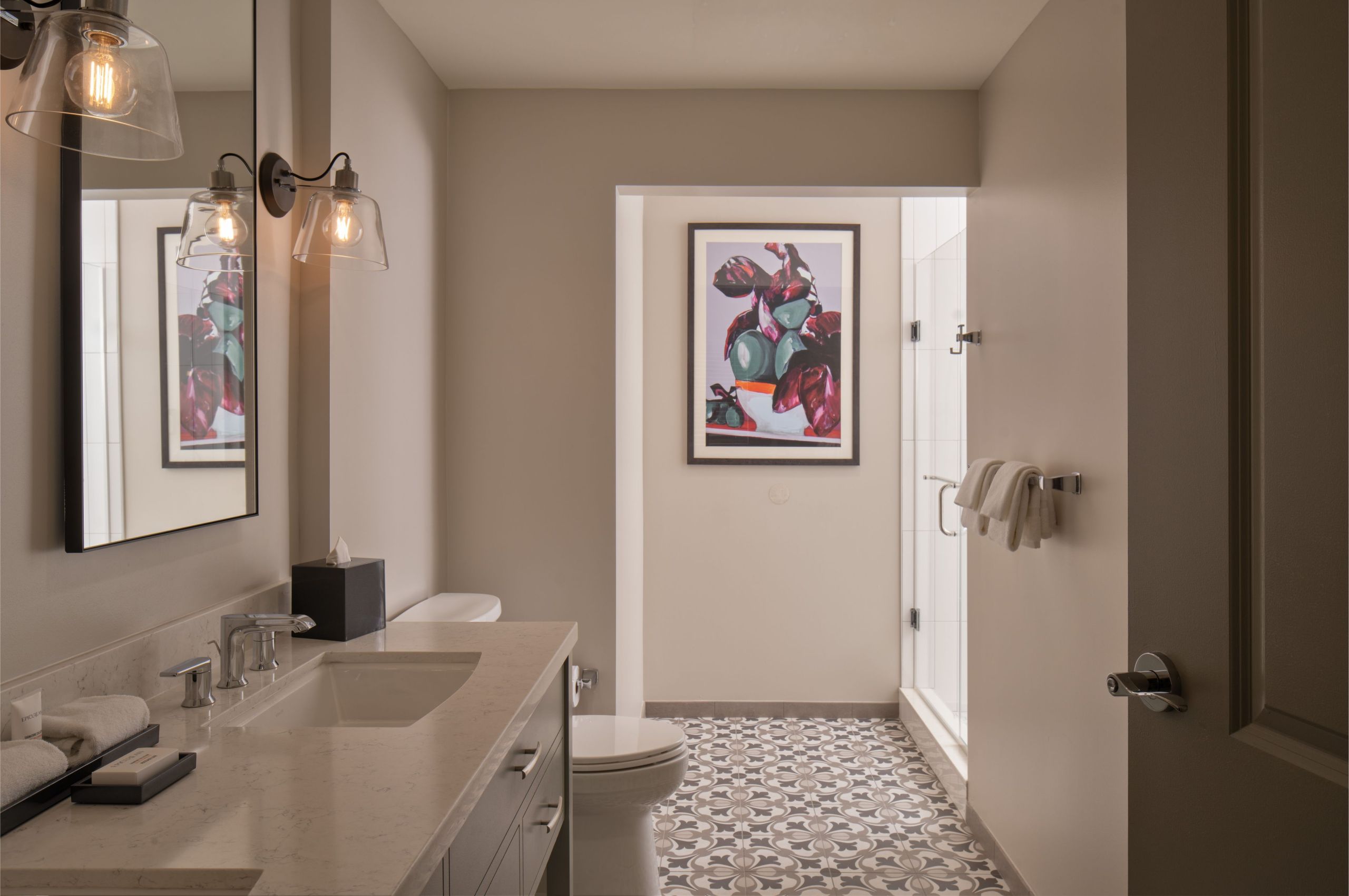 A renovated bathroom with hand laid tile and glass walk in shower of a historic hotel apartment in Hyde Park District in South Tampa Florida across from Epicurean Hotel